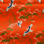 Vibrant orange polyester silk fabric adorned with elegant cranes and lush tree patterns, used to handcraft lanterns in Hoi An.
