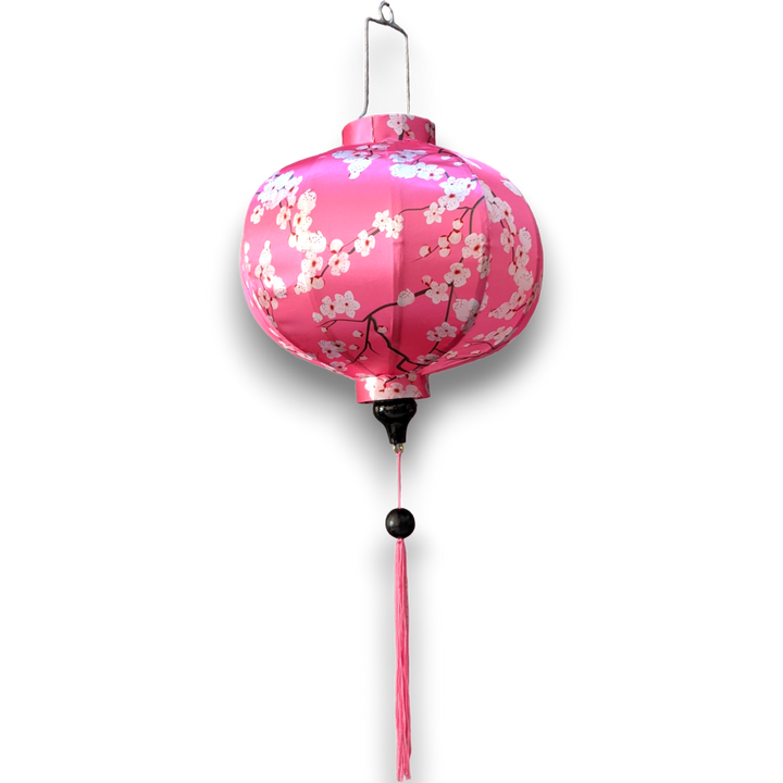 Round Vietnamese Lantern with pink tassel and white blossoms against a bright pink background. 