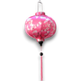 Round Vietnamese Lantern with pink tassel and white blossoms against a bright pink background. 