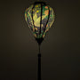 Glowing silk lantern with floral and bird design on a black background