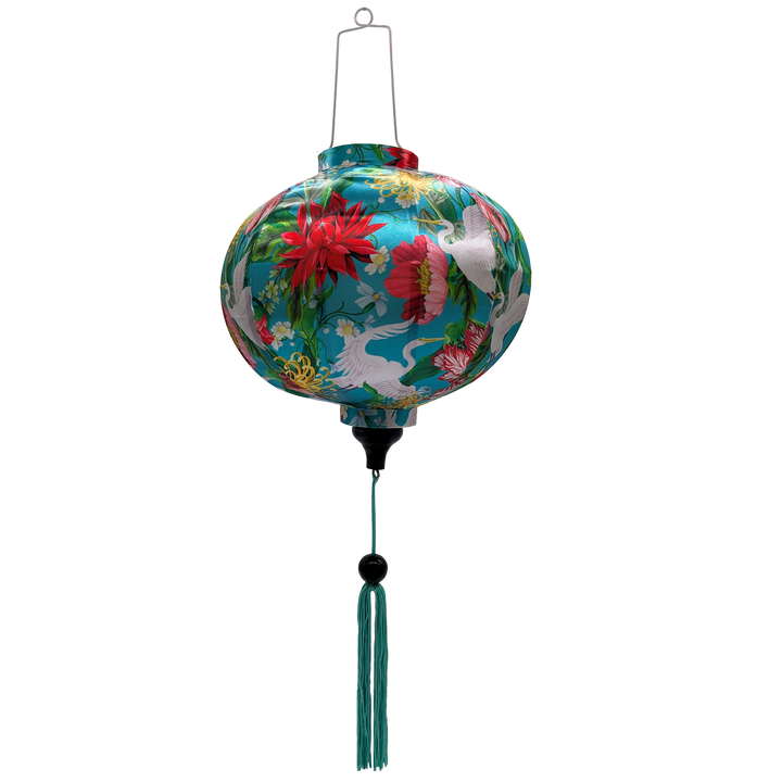 Round shape Vietnamese silk lantern featuring vibrant cranes & floral print surrounded by a lush flowers.