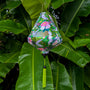 Teardrop shaped lantern featuring cranes in flight, swirls and patterns in various greens hanging in front of wet large green leaves