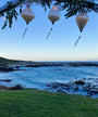 White plain silk lanterns hanging above a scenic coastal view with ocean and sky.