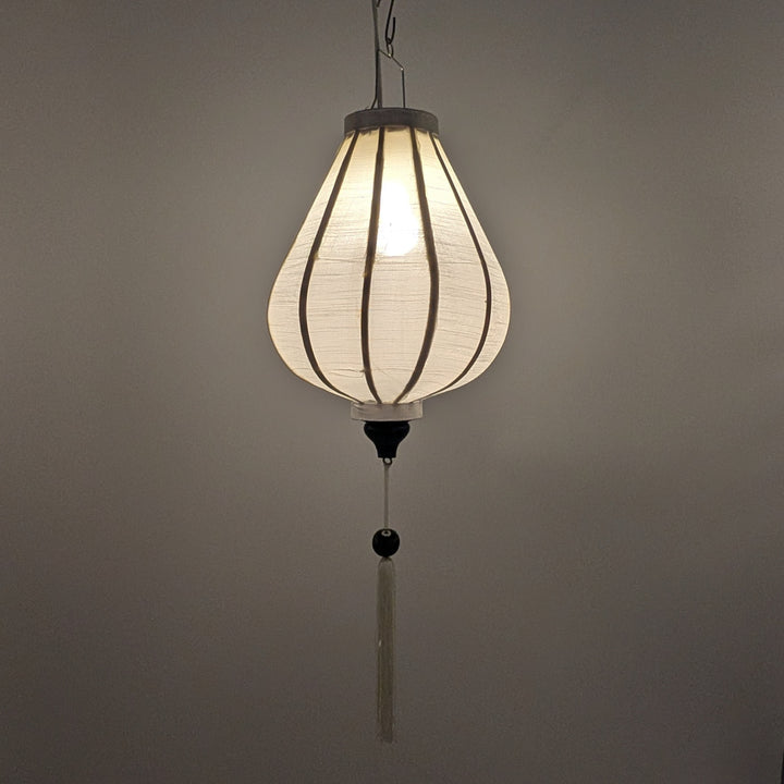 A hanging white poly linen lantern with a garlic shaped and a long white tassel.