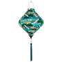 Lozenge shaped lantern with green and blue pattern on a teal blue background