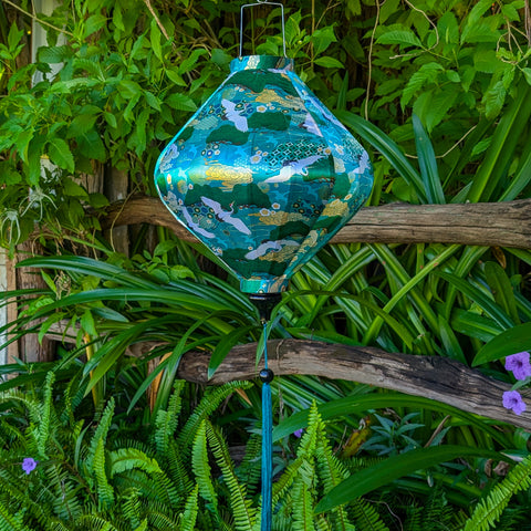 Lozenge shaped lantern hanging among green foliage