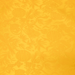 Close up of jacquard silk fabric with intricate patterns of flowers, bamboo, lanterns and symbols in a bright yellow colour.