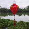 Balloon shaped lantern hanging outdoors with the Thu Bon River with a print of large golden yellow koi fish and calligraphy.