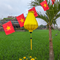 Yellow Plain silk Vietnamese lantern handmade in Hoi An set against rice fields and a banner of Vietnamese flags.