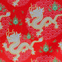 Red fabric with gold dragons and green flames on a red background
