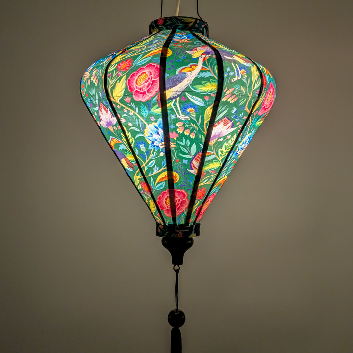 Glowing diamond shaped lantern with floral and bird pattern on a green background