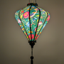 Glowing diamond shaped lantern with floral and bird pattern on a green background