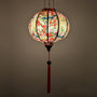 Round glowing silk lantern with floral and bird pattern on a cream background
