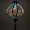 Glowing Lozenge shaped lantern featuring a print of birds in graceful flight, set against a sleek black background adorned with rolling waves, floating flowers and intricate gold illustrations.