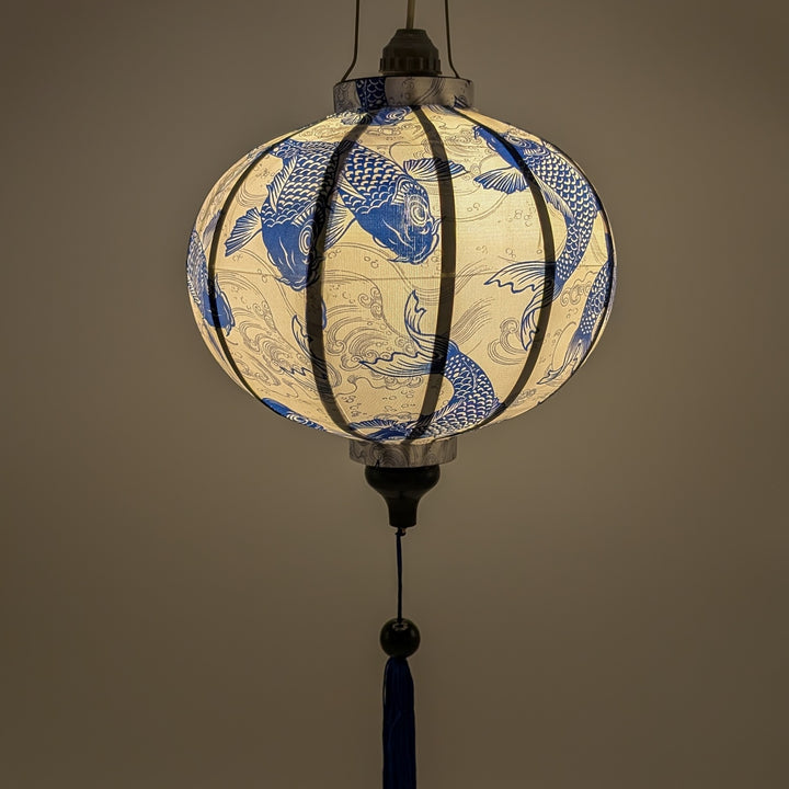 Glowing round lantern with Blue Koi print, featuring a pattern of intricately detailed koi fish swimming amidst silver swirling water currents. 