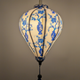 Glowing balloon shaped Vietnamese silk lantern with blue floral patterns on a white background