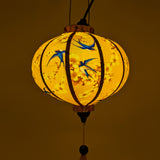 Glowing Round yellow Vietnamese lantern with blue swallow birds in flight perfect for cozy decor.