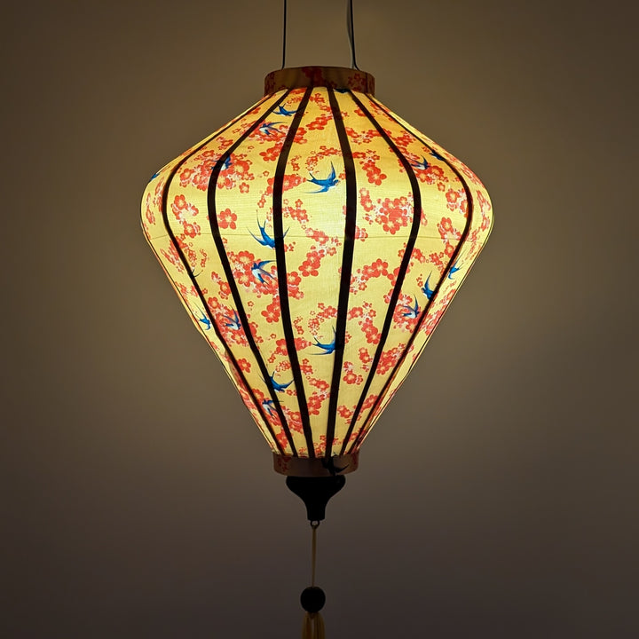 Glowing diamond shaped lantern with floral and bird pattern on a yellow background