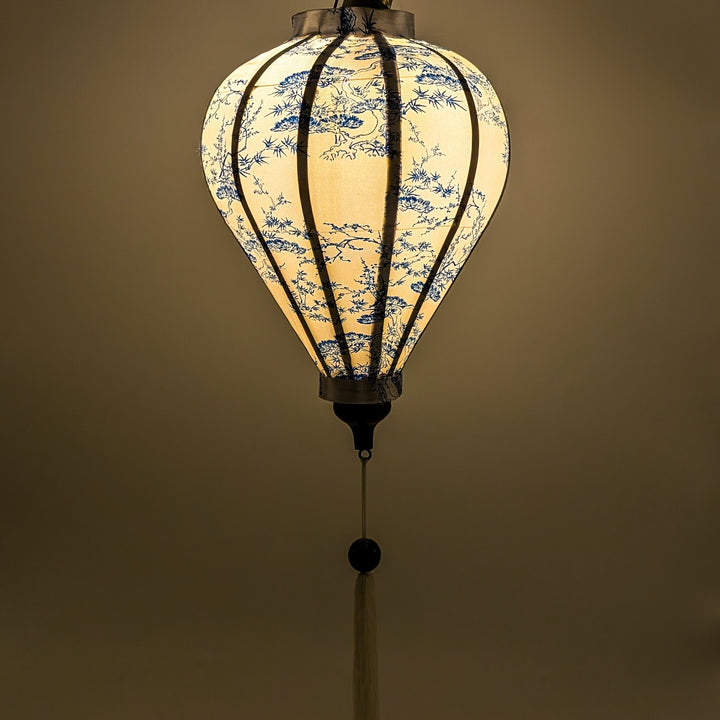 Glowing Balloon shape Vietnamese silk lantern with white fabric and blue bonsai tree print.