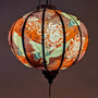 Glowing round Vietnamese lantern featuring cranes and chrysanthemum flowers.