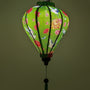 Glowing Vietnamese silk lantern for sale with green background adorned with elegant white cranes in flight, their wings gracefully spread with black and blue accents. 
