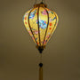 A beautifully illuminated yellow Hoi An silk lantern adorned with intricate blue cranes, delicate pink cherry blossoms, and festive red lantern motifs. The warm glow enhances the elegance of the hand-painted details, while the traditional wooden frame and golden tassel add a classic touch. This lantern brings a cozy ambiance, perfect for home decor, cultural celebrations, or thoughtful gifts.