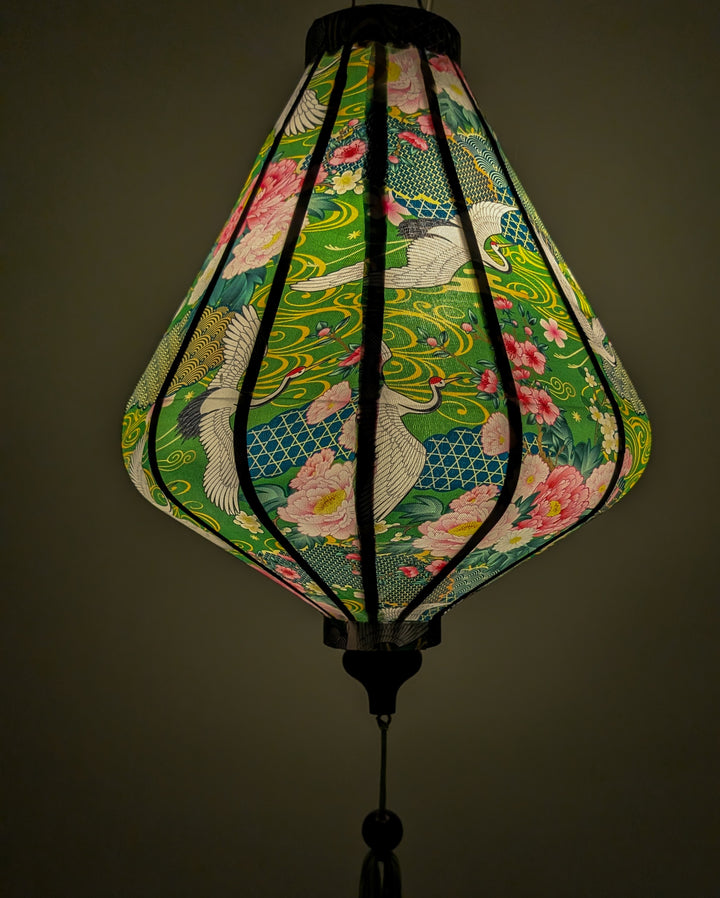 Lantern with a light inside with floral and cranes creating a green glow.
