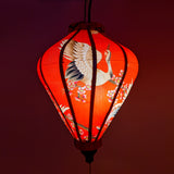 Vietnamese silk lantern with red-headed cranes on a bold red background creating a red glowing hue.