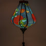 Close up of a glowing Teardrop shaped lantern with green and blue dragons on a black backdrop.