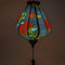 Close up of a glowing Teardrop shaped lantern with green and blue dragons on a black backdrop.