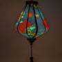 Close up of a glowing Teardrop shaped lantern with green and blue dragons on a black backdrop.
