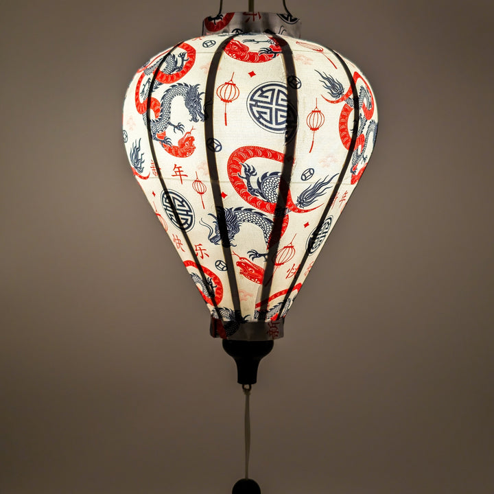 A close up of a glowing balloon shaped lantern featuring entwined red serpentines and black dragons surrounded by lanterns, symbols with a lightbulb inside.