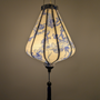 Glowing Teardrop shaped Vietnamese silk lantern with blue and white pattern on a plain white background.