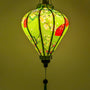 Glowing Vietnamese silk lantern with black branches with red and yellow flowers, red fans as well as golden circular motifs with intricate geometric designs.