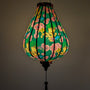 Glowing Vietnamese silk lantern in Garlic shape with floral and fire dragon design on a dark green background