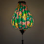 Glowing Vietnamese silk lantern in Garlic shape with floral and fire dragon design on a dark green background