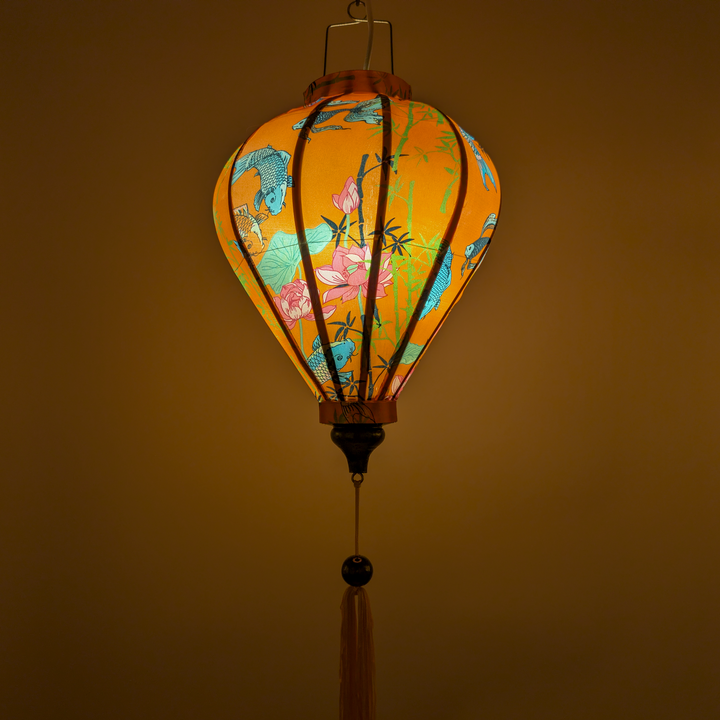 Glowing Vietnamese silk lantern with koi fish, bamboo and lotus flowers on a orange backdrop