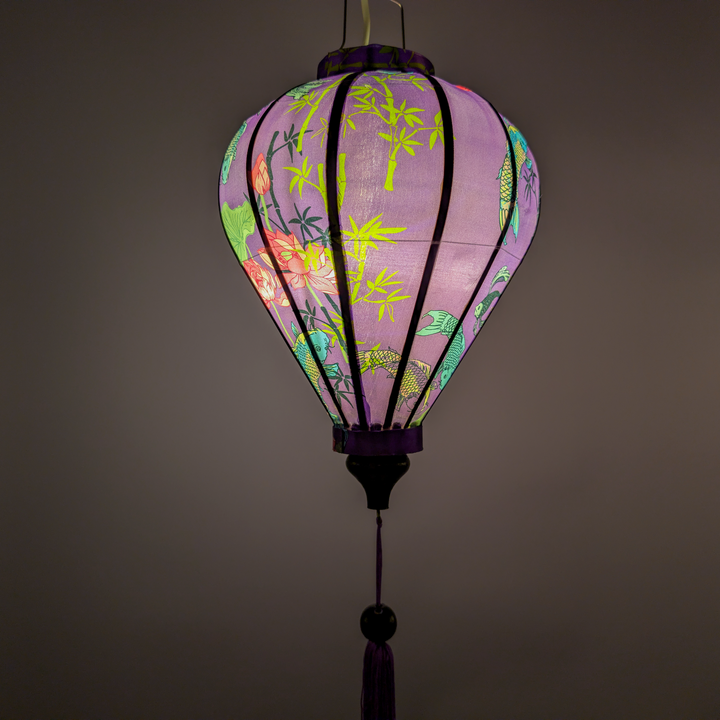 Glowing Vietnamese silk lantern with koi fish, bamboo and lotus flowers on a purple backdrop