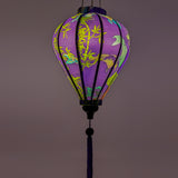 Glowing balloon shaped lantern with a print of koi fish swimming around bamboo reeds and pink lotus flowers on orange background.