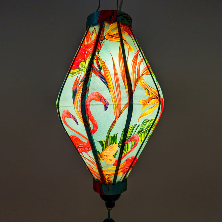 Up close of a glowing Tube shape lantern with flamingos on blue.