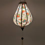 Up close glowing Garlic shaped Vietnamese Lantern with a beautiful illustration of flowers in blue, green and orange colours against cream background.