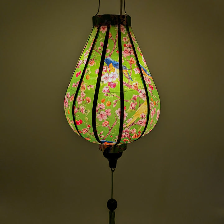 Glowing Garlic shape lantern with green hue featuring blue and yellow fly catcher birds sitting in a cherry blossom tree.