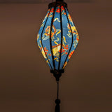 Up close glowing Tube shaped Vietnamese Hoi An Lantern featuring golden cranes amongst red and gold lined flowers with subtle grey shimmer of a geometric pattern against black.