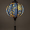 Glowing round Vietnamese lantern with a print of golden yellow dragons and flowers set against a grey sea pattern of swirls on a rich black background.