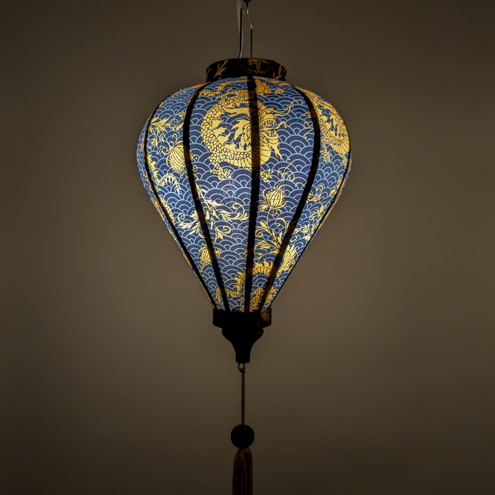 Glowing Vietnamese silk lantern with golden yellow dragons on a black background with grey swirls