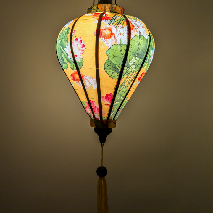 Decorative lantern with gold fish and lotus flowers on a yellow creating a yellow glow.