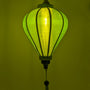 A green balloon shape Vietnamese lantern made from jacquard silk glowing.