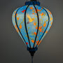 Glowing balloon shape Vietnamese silk lantern featuring a print of hummingbirds in flight with red and pink flowers creating a blue hue.