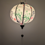 Glowing round Vietnamese silk lantern with koi fish and bamboo design on a white background