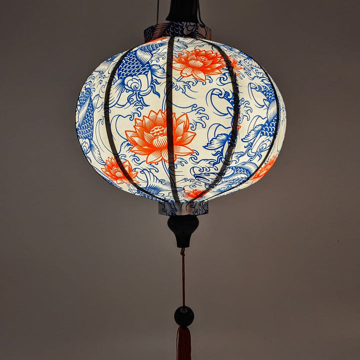 Handmade glowing Hoi An lantern featuring koi fish and vibrant red lotus flowers, symbolizing luck and prosperity.
